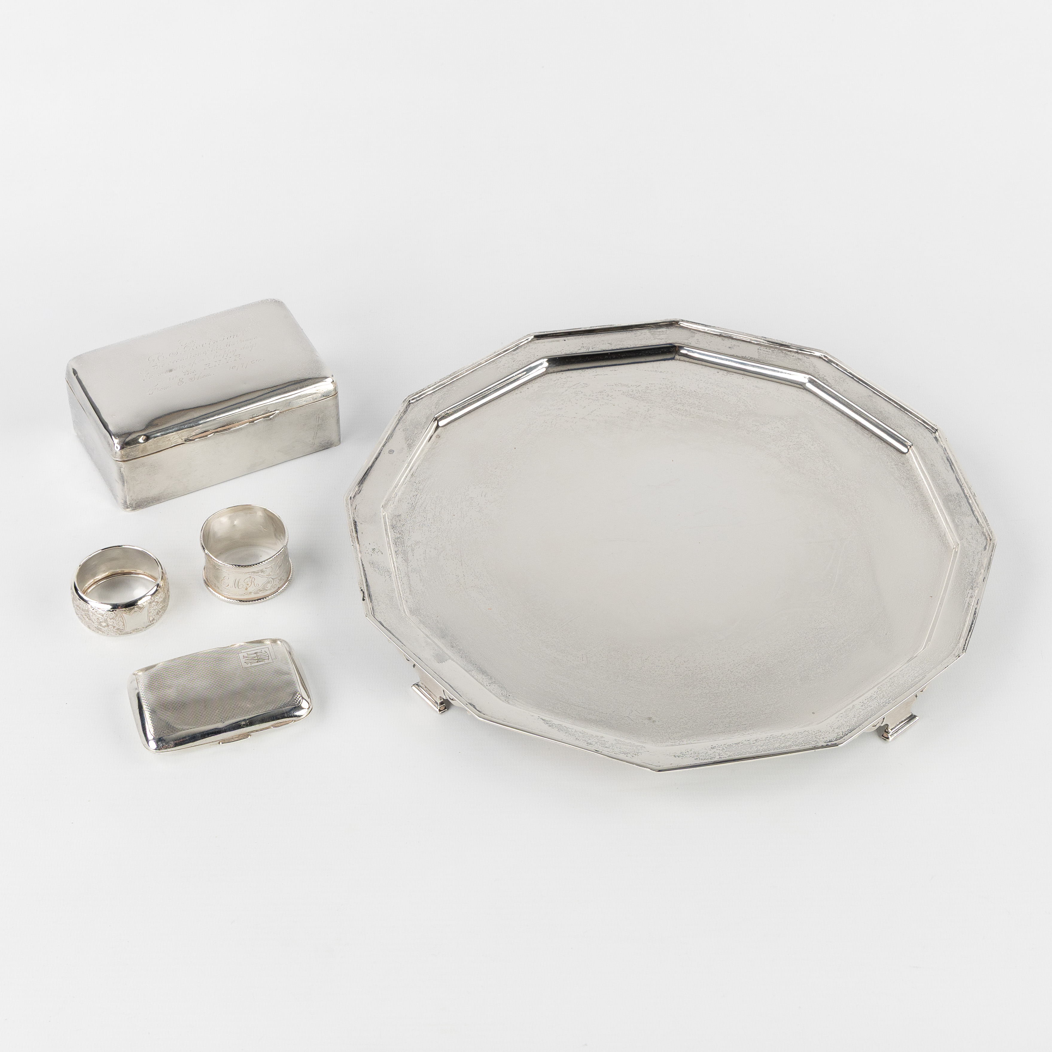Five silver accessories, with an assiette volante, two napkin rings, a cigar box, and a cigarette case, England. Silver, 1,398kg (L:34 x H:2.5 cm)